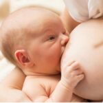 Majka s većim dojkama doji bebu uz pridržavanje dojke rukom