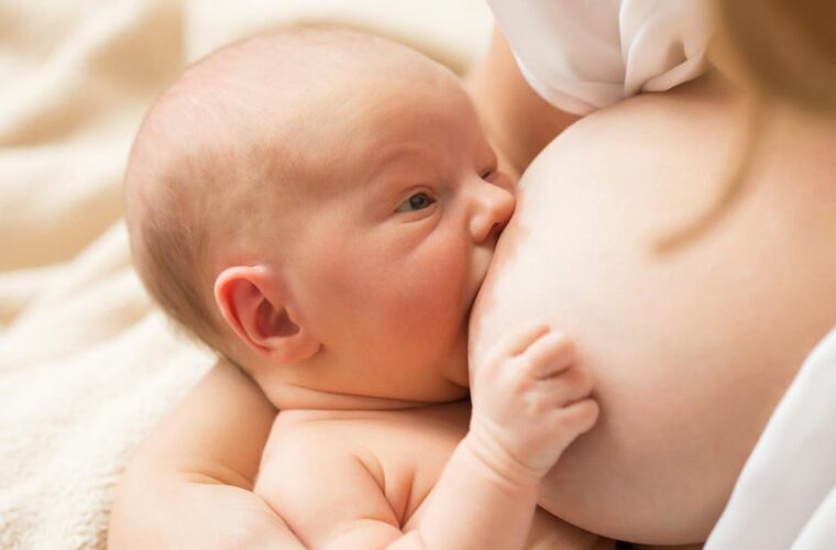 Majka s većim dojkama doji bebu uz pridržavanje dojke rukom