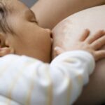 Majka s većim dojkama doji bebu uz pravilnu podršku dojke i položaj tijela